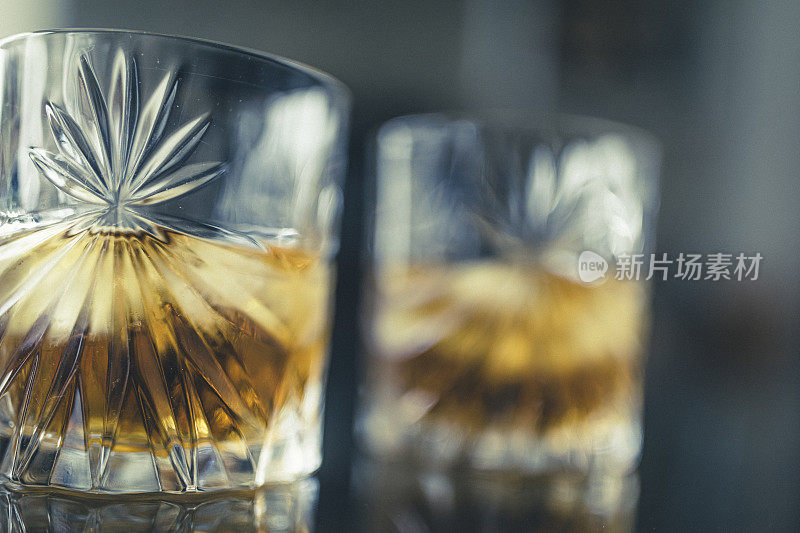 在一张玻璃桌子上，两杯加冰的苏格兰威士忌正等着你品尝。