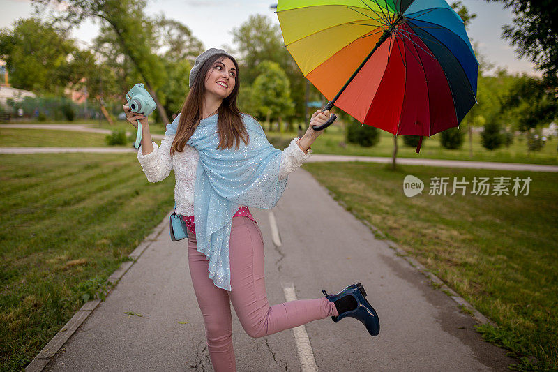 漂亮凉爽的女人带着五颜六色的雨伞在秋天的一天