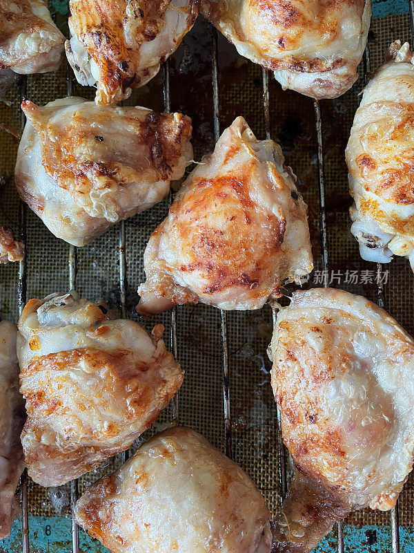 形象酥脆，金黄的鸡腿放在烤架上，皮脂肪烹饪和滴在下面的硅胶垫，俯瞰