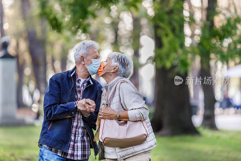 一个快乐的老夫妇的肖像，谁是在公园散步和交换可爱的词在病毒时间。