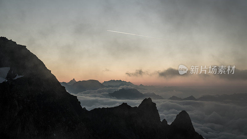 雄伟的尖峰映衬着夕阳的天空。雪山景观，云海山谷