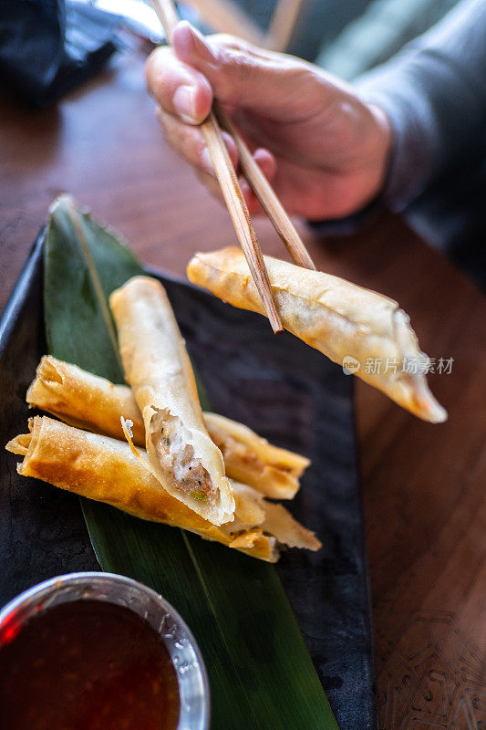 一位妇女用筷子吃亚洲食物