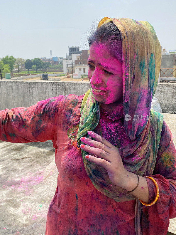 印度妇女穿着沙尔瓦·克米兹的传统服装，涂满油漆粉，在胡里节的色彩和爱漆大战中胡闹