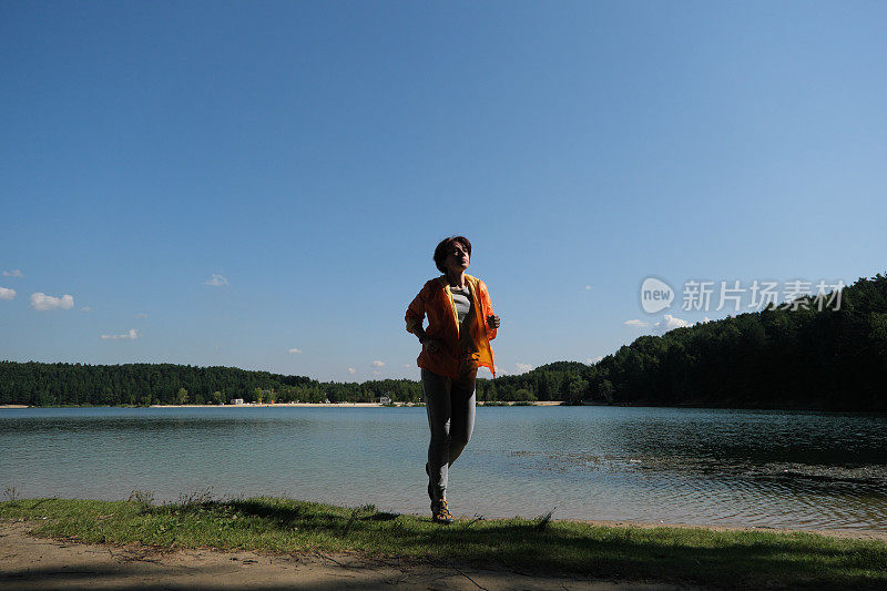 成熟的女人在夏日的自然公园里奔跑