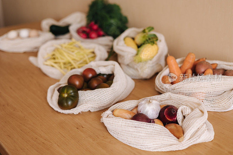 蔬菜装在可重复使用的环保棉袋里，放在木桌上。零浪费购物理念。帆布杂货袋与西红柿，胡萝卜，土豆。塑料免费项目