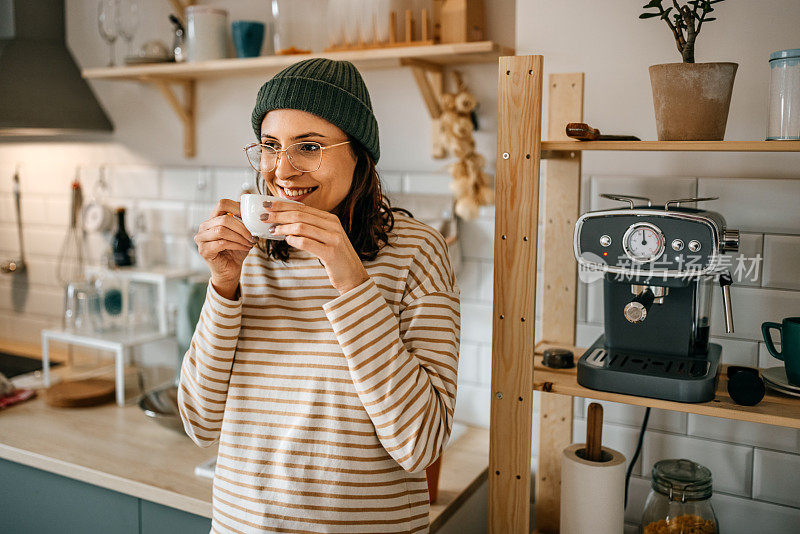 微笑的女人拿着咖啡杯站在厨房里