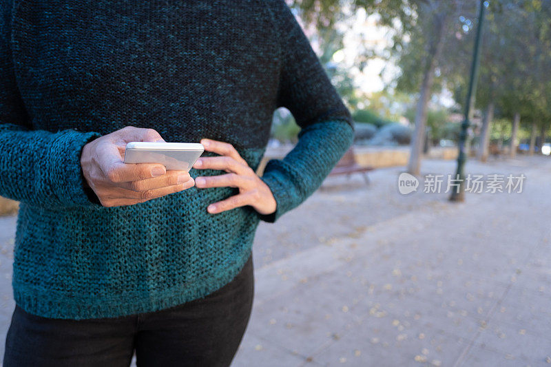 一名女子在公园里使用智能手机焦急地等待。