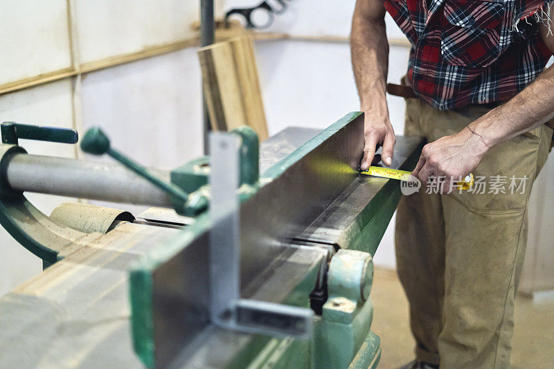 木匠在木工车间用仪表测量表面的表面刮刀。