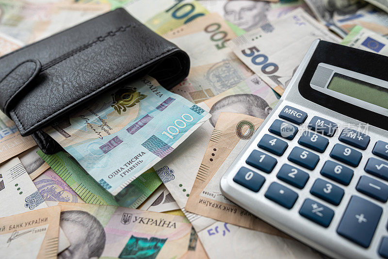 桌子上放着许多欧元格里夫纳的钞票，旁边是一个装有钱的钱包和一个计算器的桌子
