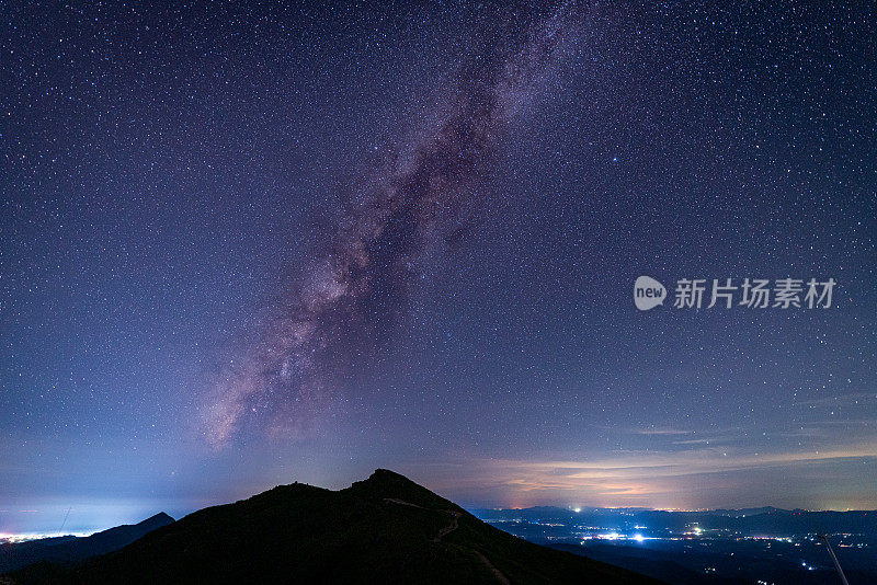 银河和粉红色的光在山上。晚上多彩的景观。