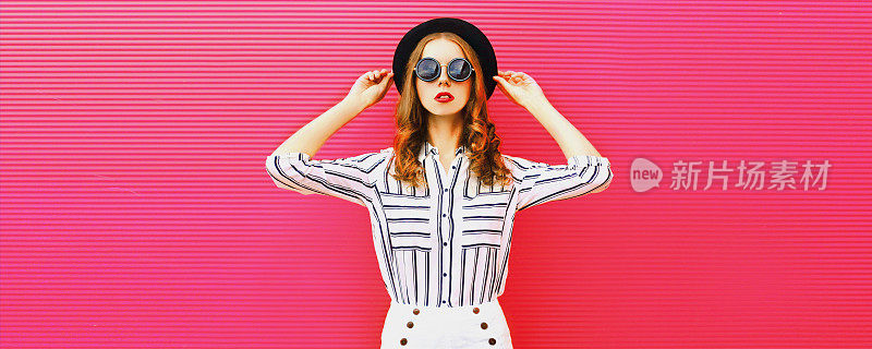 肖像美丽的女人模型戴着夏天的帽子，白色条纹衬衫在粉红色的背景