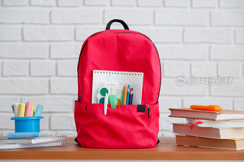 回到学校，背包里装着学校用品和文具，课本和笔记本放在桌子上。