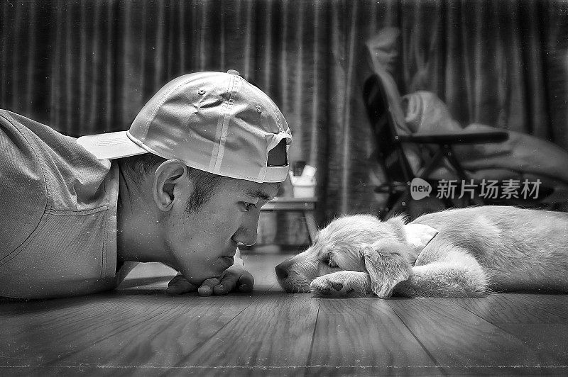 一名韩国男子和一只可爱的狗躺在一所房子的地板上的灰度肖像