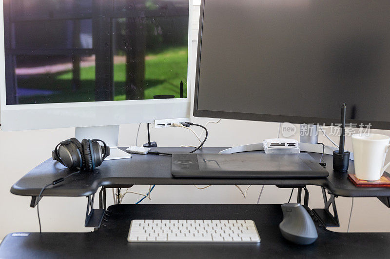 现代双显示器计算机在一个站立的办公桌在办公室