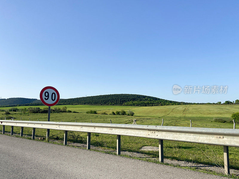 乡村道路和路标，有清晰的天空和山脉背景