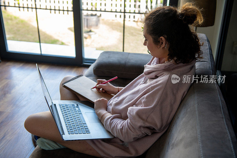 年轻女子在沙发上用电脑工作