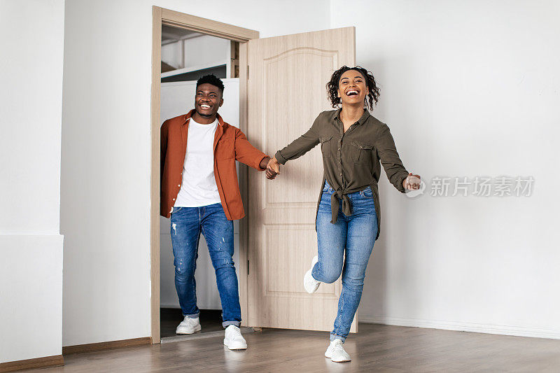 兴奋的非裔美国夫妇跑进房间进入新房