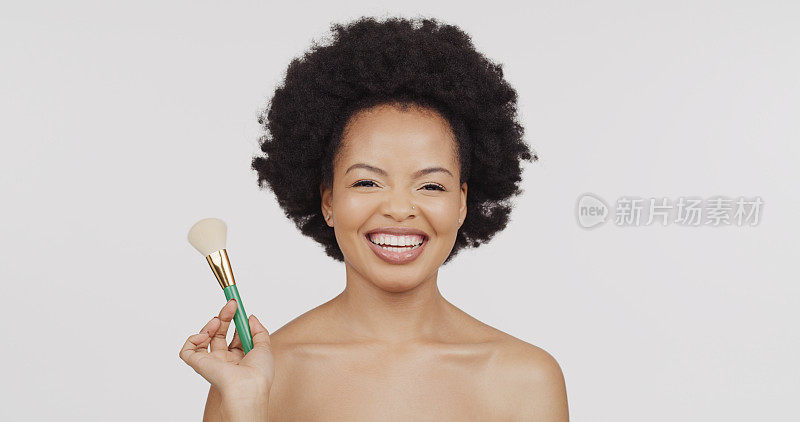 美容，化妆和黑人妇女用刷子在一个工作室的自然美容脸例行公事。快乐，微笑和肖像的非洲女模特与化妆品产品孤立的灰色背景。