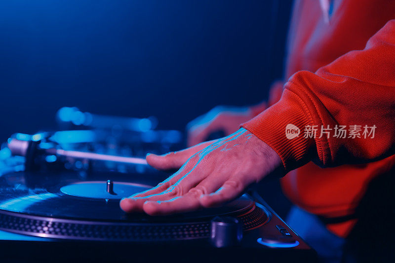 嘻哈DJ在转盘上刮黑胶唱片。音乐节目主持人在夜总会的派对上录制唱片
