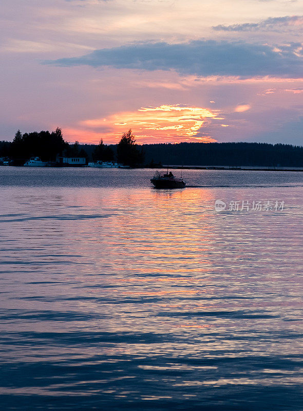 芬兰塞马湖上明亮的夕阳和一艘在夕阳下的机动渔船。夏天的风景