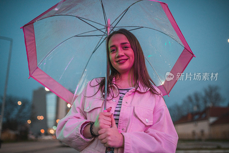 一个带着微笑的女人在雨夜撑着伞散步的肖像