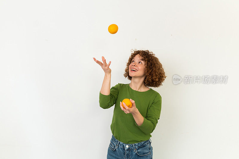 一个美丽的红发女孩拿着橙子的工作室肖像