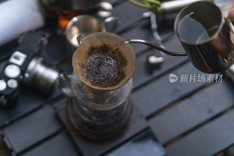 这是一张咖啡酿造过程的顶级照片，背景中有选择性地关注了水壶和咖啡机，以及研磨机和炉子