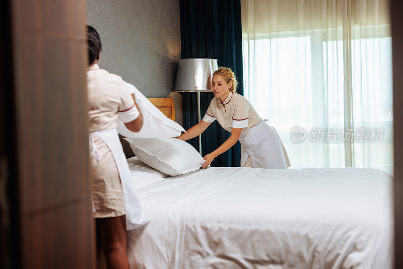 多种族旅馆的女服务员把枕头放在一起