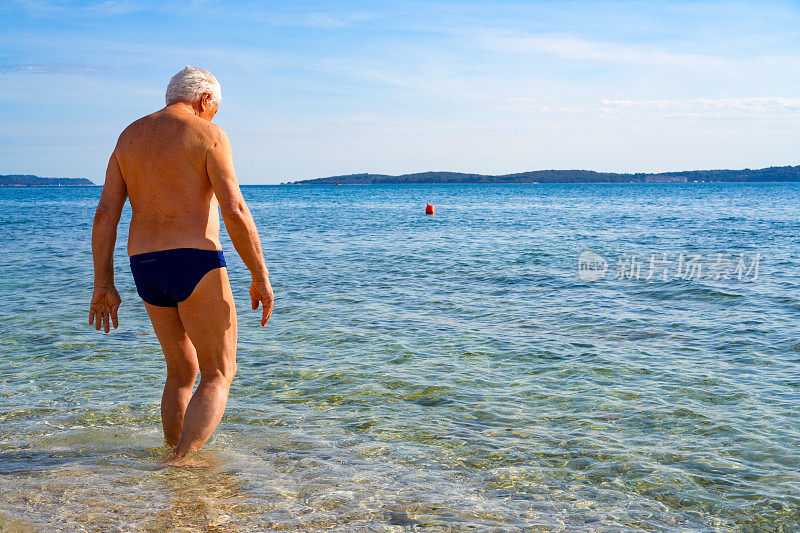 老年男子和帕金森病患者在海水中散步。
