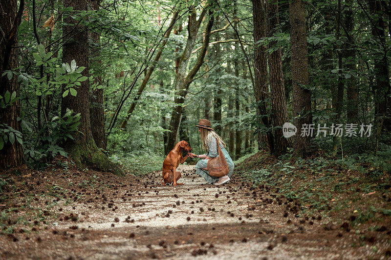 年轻女子和匈牙利猎犬在树林里