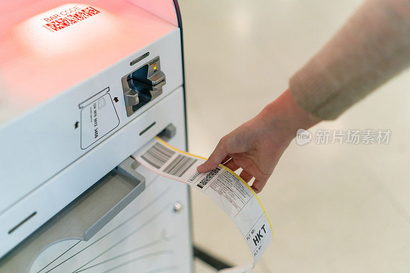 打印的自助登机行李标签特写。一名年轻的亚洲女子在机场自助自助值机亭办理登机手续。准备好旅行了。