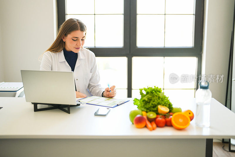 年轻的金发女郎是一名营养学家，她在办公桌前制定了一个饮食计划，面前放着水果