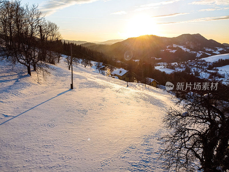 日落时的冬日风景，白雪覆盖的山丘和晴朗的天空。