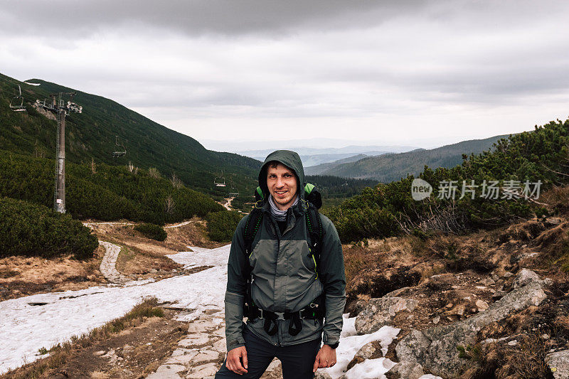 这家伙是个背包客，背包里装着旅游装备和智能手表。男人的男性肖像，在山中旅行。穿着保暖运动服在户外徒步旅行的人。生活方式人物摄影，旅游理念。