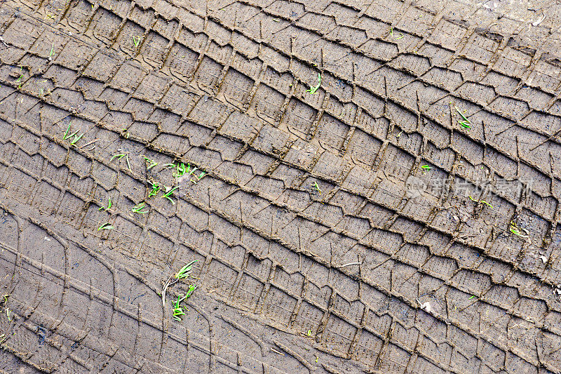 汽车轮胎的胎面花纹印在泥里，车轮保护器的纹路印在泥里，轮胎印在泥里