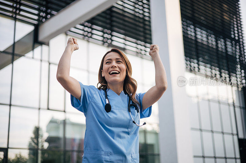 成年女医生非常高兴和兴奋的举手做胜利的手势