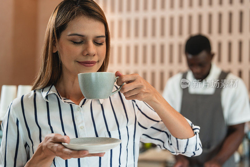 一位热爱咖啡的年轻女子在一家黑人咖啡馆里享受着咖啡的香味和味道。