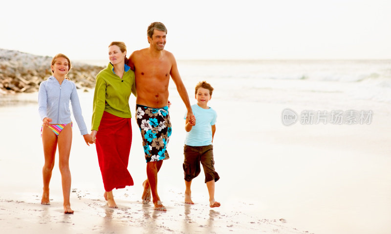幸福的一家人在度假，漫步在海边