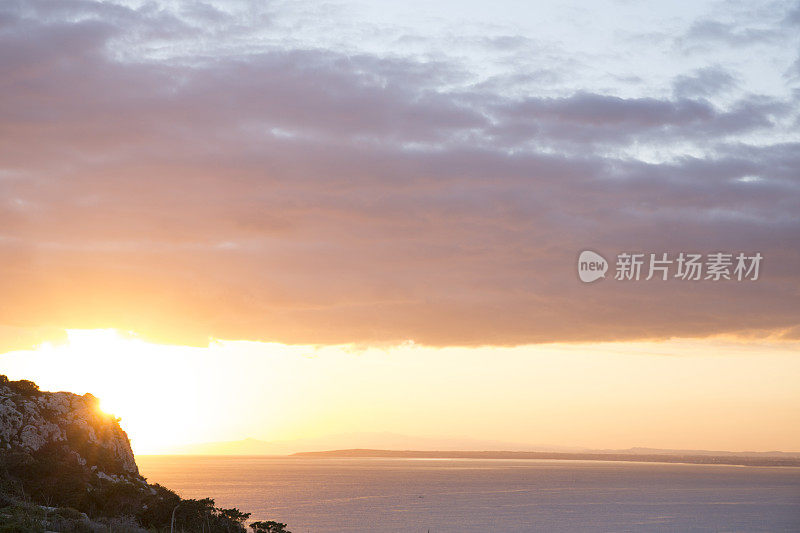 太阳升起在海面和岩石峭壁上