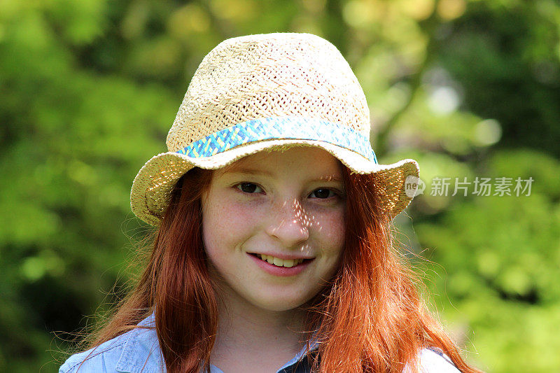 漂亮的年轻快乐的女孩在花园阳光戴着草帽