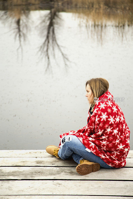 年轻女子用毯子在湖边休息
