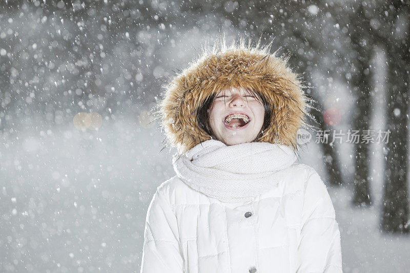 雪下穿着白色夹克的漂亮少女