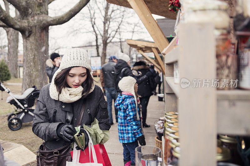 年轻女子与钱包在公共户外市场在冬天。