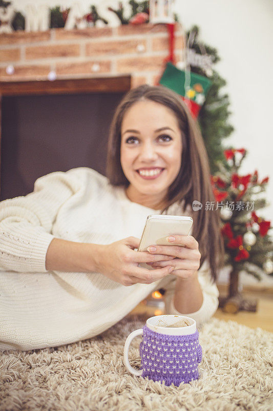 壁炉边拿着手机的女性