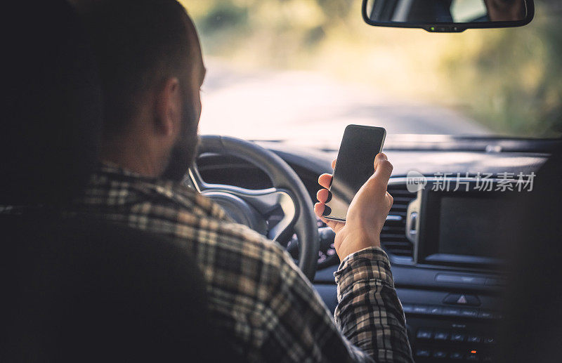 一个男人坐在车里用智能手机