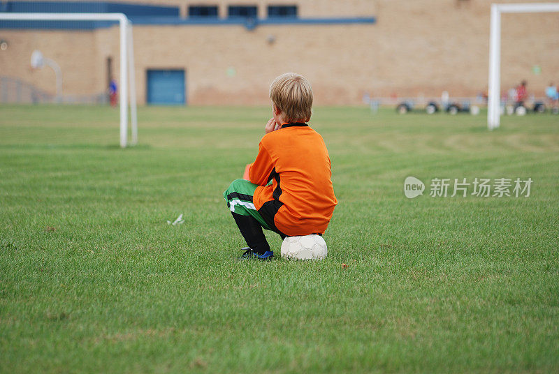 不活跃的年轻足球运动员在等待，幼稚的气球在激励
