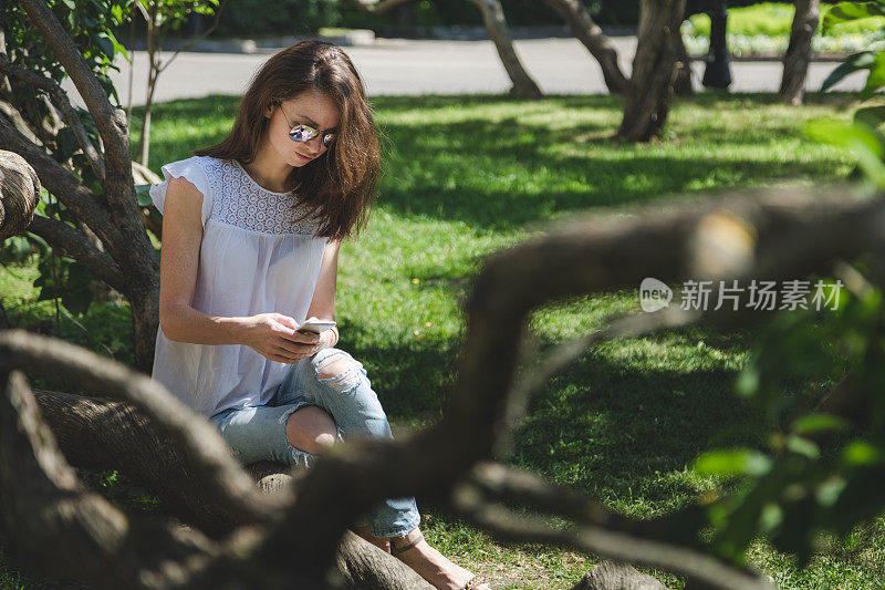 一位美女在公园里用智能手机