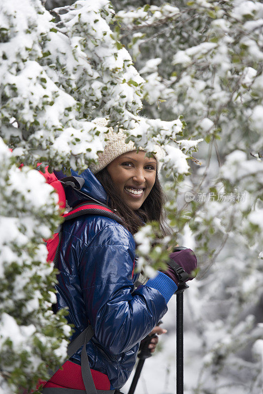 在白雪覆盖的森林里徒步旅行的女人。