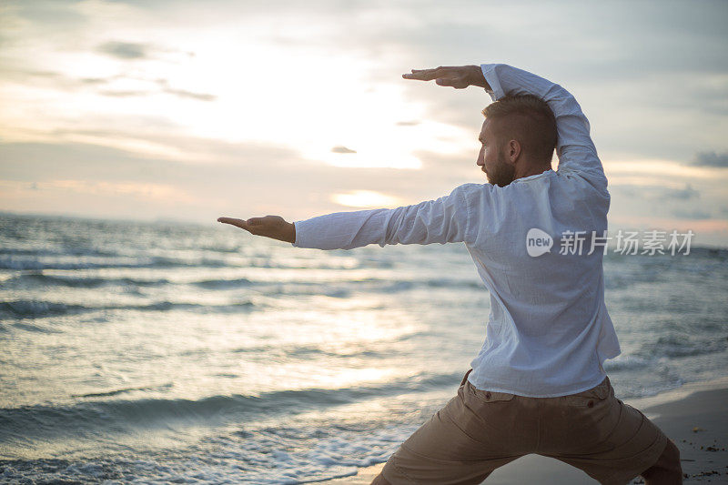 日落时分，一名男子在海滩上练太极