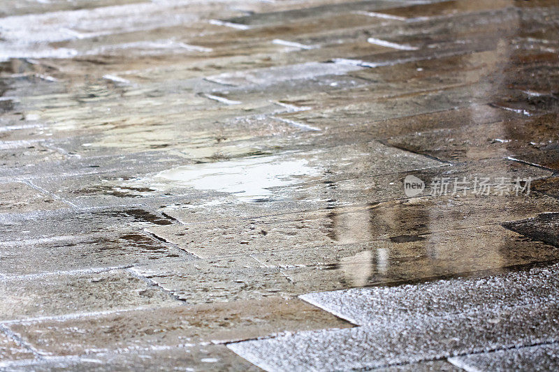潮湿的街道铺石地板，水坑和倒影。